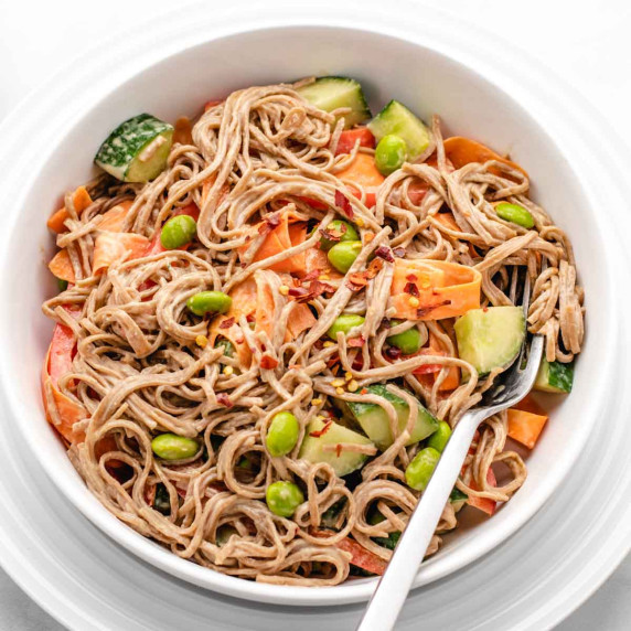 Soba noodles, edamame, cucumber, carrots in a bowl with a tahini dressing.