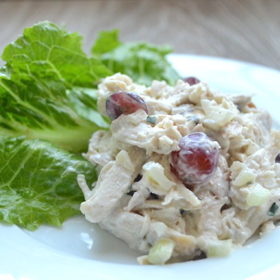 Closeup of tarragon chicken salad with red grapes and romaine lettuce leaves in the background. 