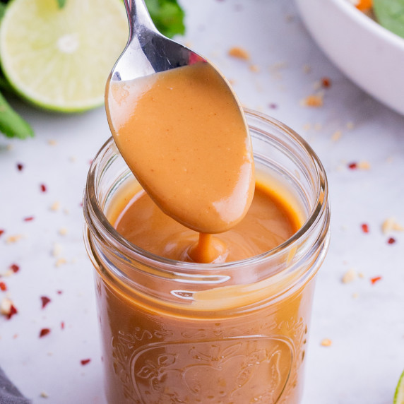 Thai Peanut Salad Dressing RECIPE served in a Mason jar with a spoon.