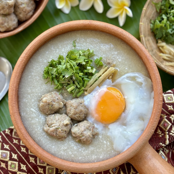 Thai congee, rice porridge, or jok, served in a clay dish with pork meatballs.