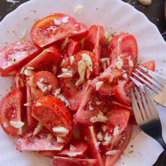 A white plate of 5-minute tomato salad with some garlic garnishing