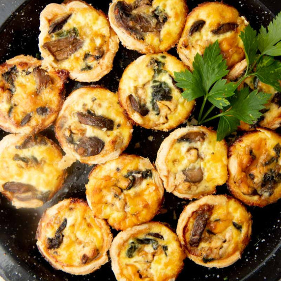 Overhead of an appetizer platter filled with spinach and feta mini quiche.