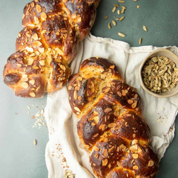 Top view of two braided loaves of Finnish pulla cardamom bread topped with toasted sliced almonds.