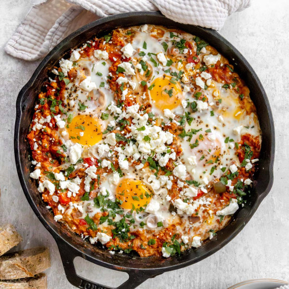 Turkey shakshuka in a cast iron skillet topped with crumbled feta and chopped cilantro. 