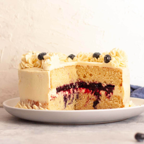 A closeup of vanilla cake with blueberry filling on a white plate.