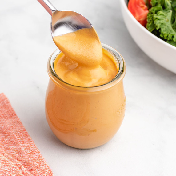 Vegan chipotle sauce in a glass jar with a spoon.