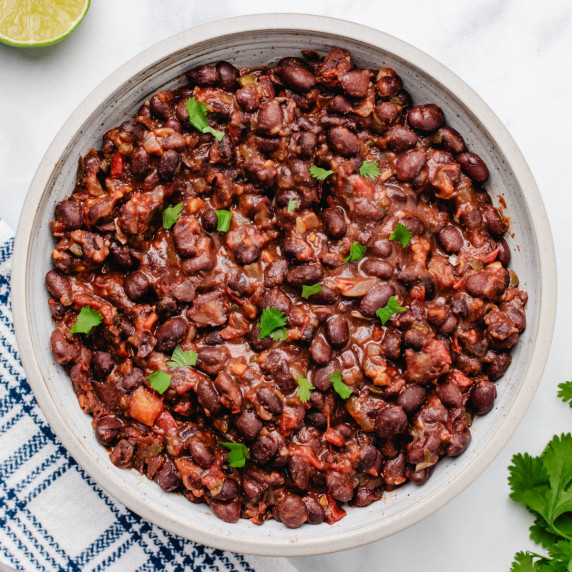 Vegan black beans with tomatoes in a bowl with chopped cilantro.