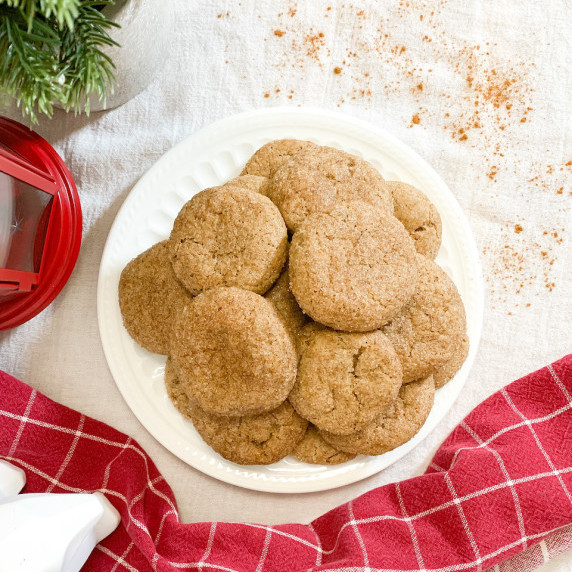 vegan snickerdoodles on a white plate with christmas decorations around it