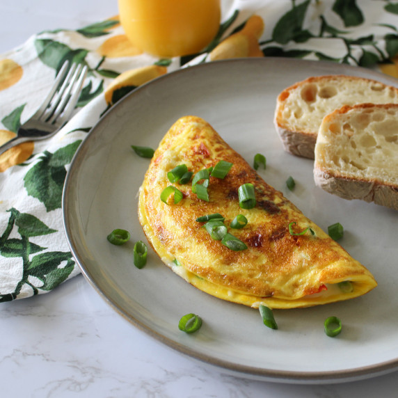 A veggie omelet topped with scallions served with toast and orange juice