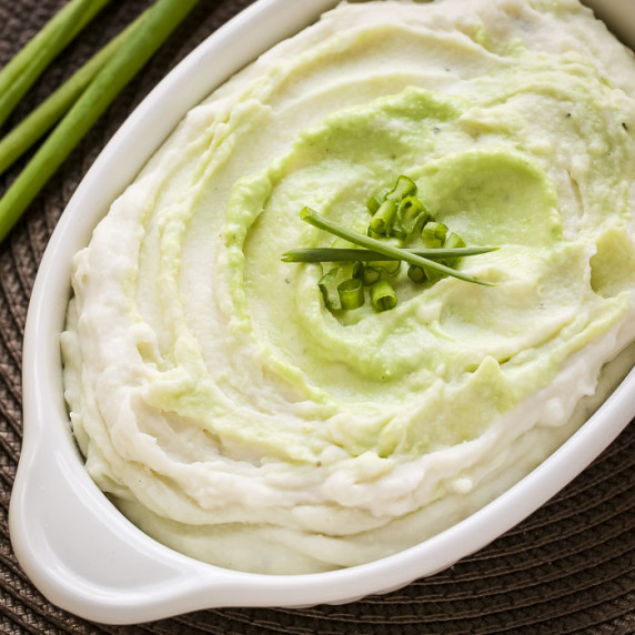 Overhead close up shot of wasabi mashed potatoes in a white baking dish garnished with green onions.