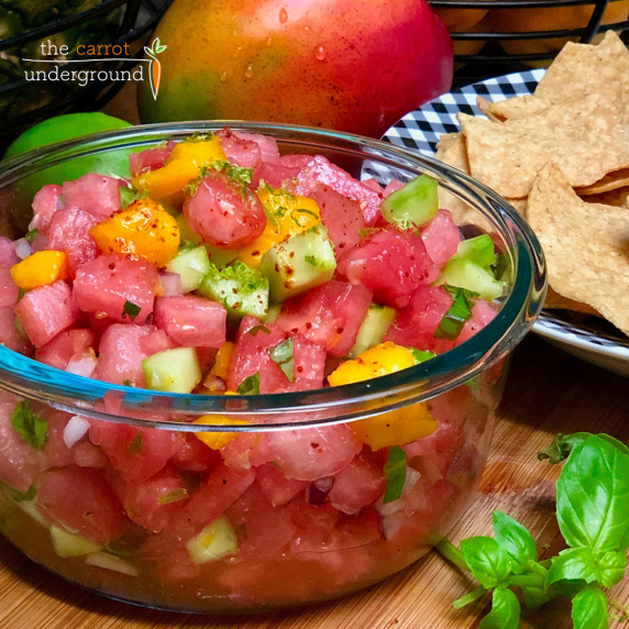 A glass bowl filled with fresh watermelon pico de gallo made with mango and cucumber. 