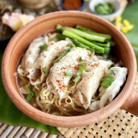 Close-up of wonton egg noodle soup with homemade wontons and choy sum.