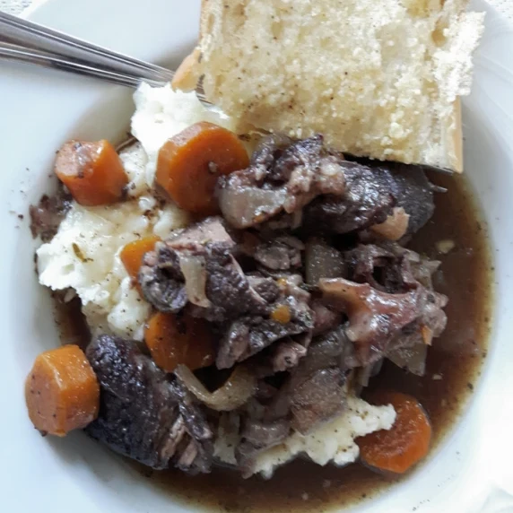 braised beef shanks in red wine with carrots and onions over mashed potatoes