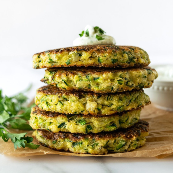 stacked zucchini fritters on parchment paper.